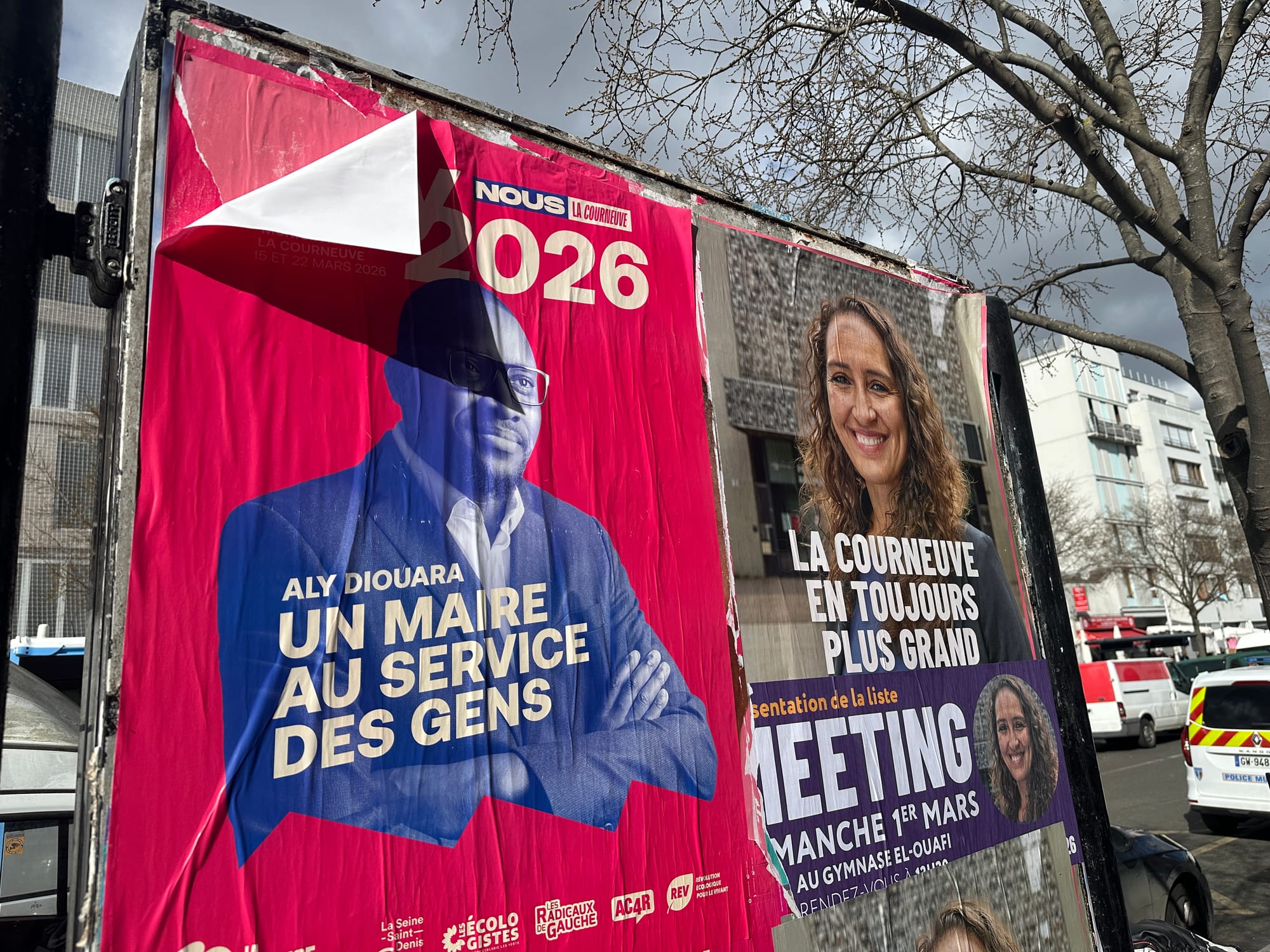 Un panneau d’affichage électoral présentant les candidats Aly Diouara (LFI) et Nadia Chahboune à La Courneuve, le 1er mars 2026. Le candidat est imprimé en bleu sur fond rose.